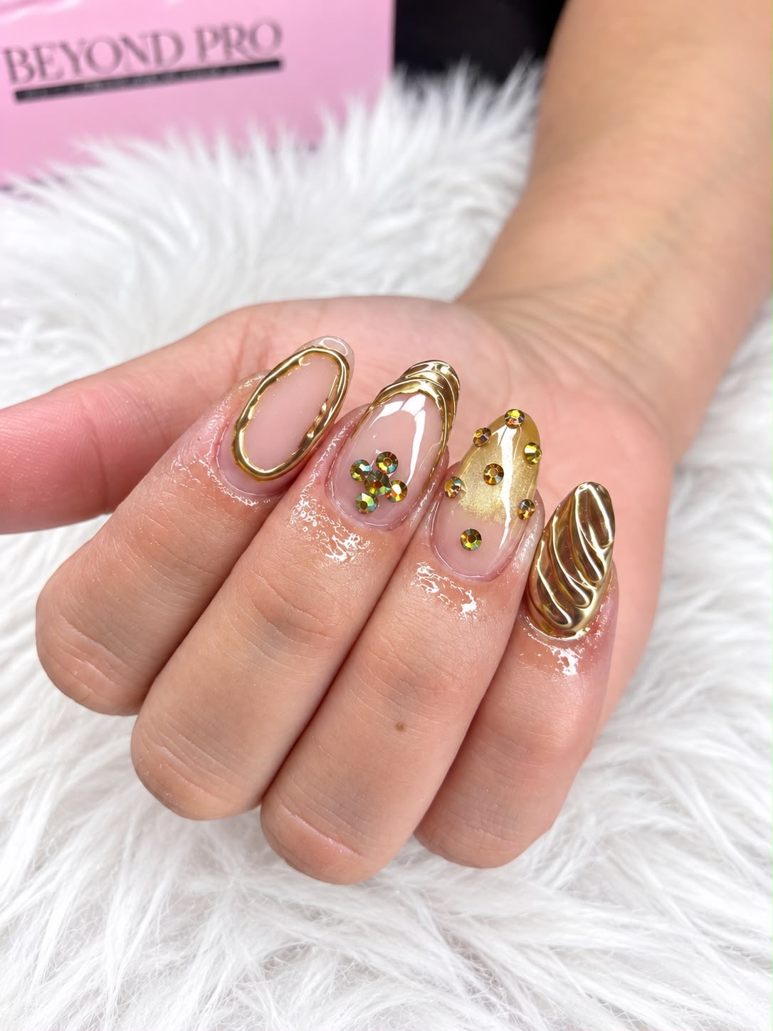 Uñas nude con remolinos dorados y cristales