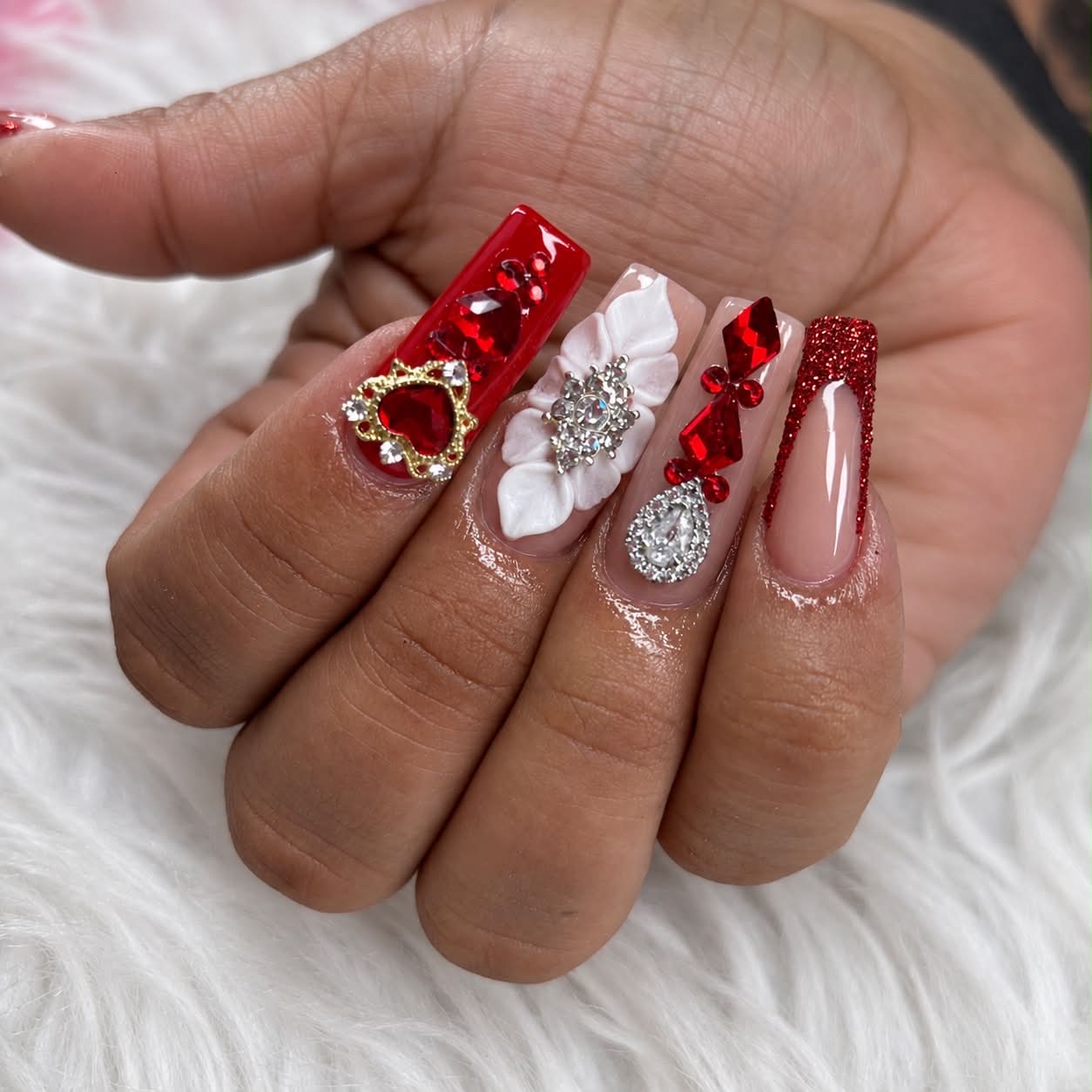 Uñas rojas con cristales y flores blancas