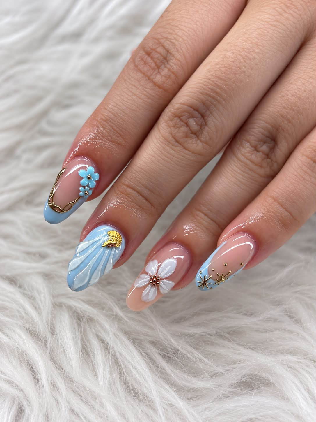 Uñas azules con flores y detalles dorados
